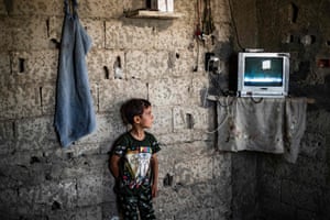 Raqqa, Syria: A Syrian boy, displaced along with his family from Deir ez-Zor, watches a screen inside the damaged building where he is living