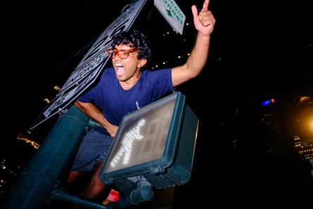 A Knicks fan cheers on top of a crosswalk light