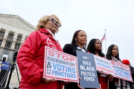 four women hold signs featuring messages such as ‘stop discriminatory voting practices’ and ‘build Black political power’