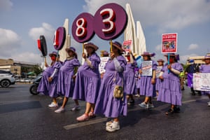 Women dressed in purple pregnancy costumes  march on a street