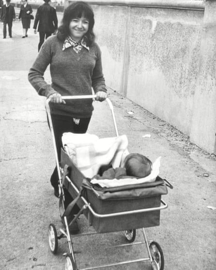 A black and white shot of Margaret Hodge walking pushing a baby in a pram while walking down the street.