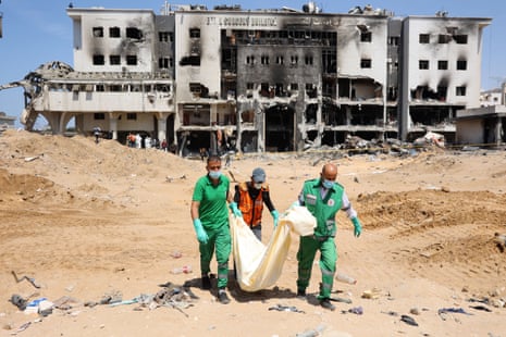 Palestinian forensic and civil defence carry a bodybag as they recover human remains at the grounds of al-Shifa hospital, on Monday.