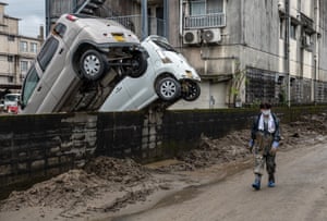 Hitoyoshi, Japan. A woman walks past cars that have been swept up against a wall after torrential rain caused the nearby Kuma River to burst its banks and flood the area. At least 60 people are believed to be dead and many more are missing after unprecedented rainfall in central Japan