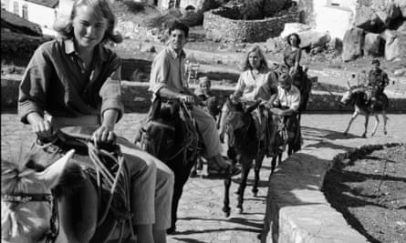 Marianne Ihlen leading Leonard Cohen and friends on donkeys along a stone path in Hydra, in 1960.