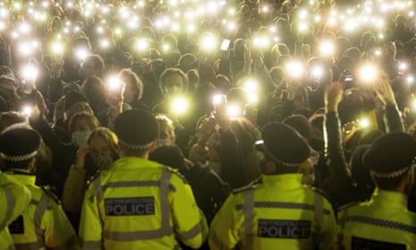 People hold up their phone torches as police attend a vigil in London in March 2021 for Sarah Everard.