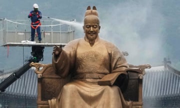Seoul, South Korea A worker sprays water onto the statue of King Sejong.