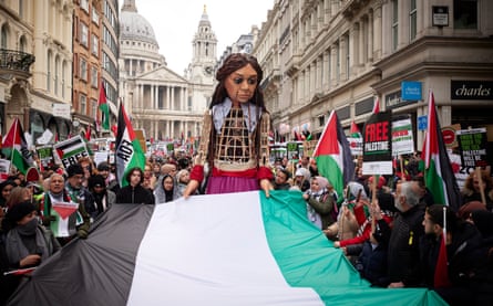 Little Amal, a 12ft giant puppet of a Syrian child refugee, accompanies the protesters in London.