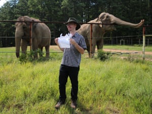 The writer holds a picture of Shirley with two elephants in the background