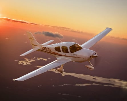 Small two-seater biplane flying as the sun sets.