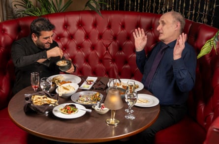 Two men facing each other at a restaurant table