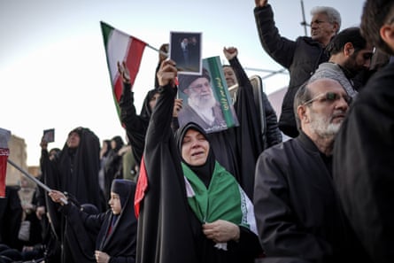 Mourners hold up pictures of the late ayatollah