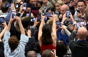 People crowd around the pope who is barely visible; many in the crowd are holding up phones to take photos or video