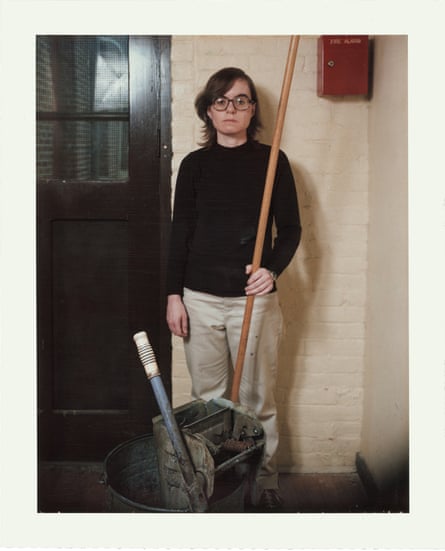 A woman in round glasses with a mop and bucket