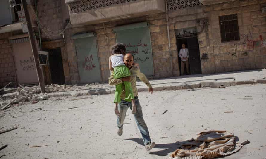 ‘You have to take care of your head and your heart after witnessing terrible things’ … a father runs out of his apartment carrying his daughter following airstrikes in Aleppo, Syria in 2012.