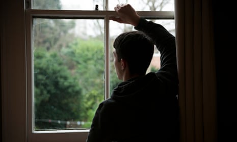 Teenage boy looking out of bedroom window, hand on window
