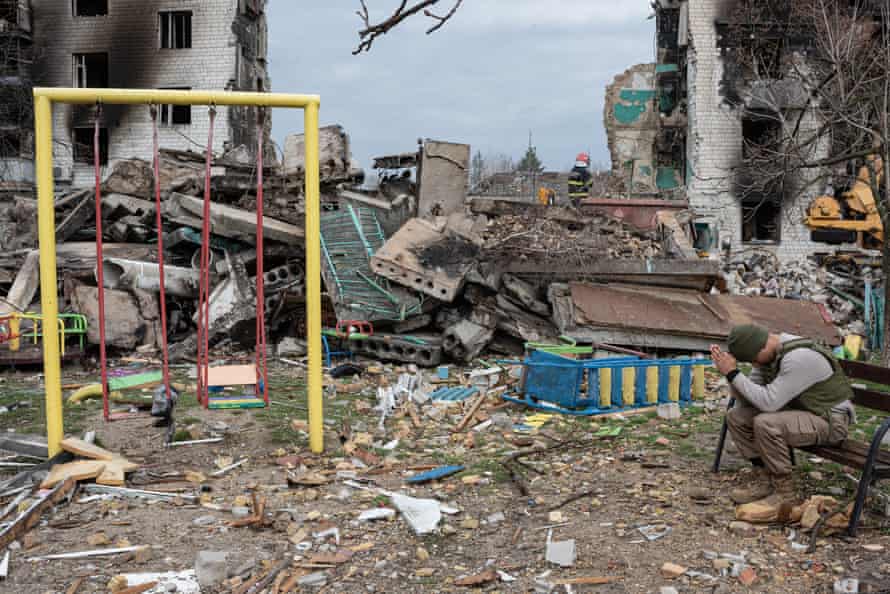 Leo, 22, a volunteer from the US, prays by the destroyed apartment building in Borodianka.