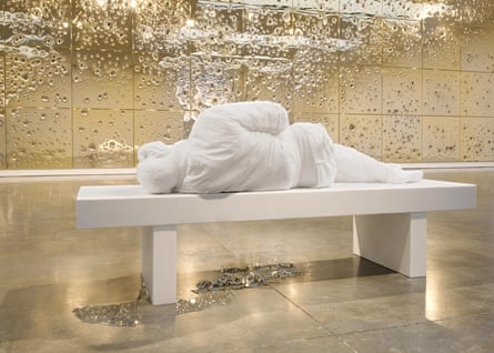 White statue of person laying on a bench in a gilded room