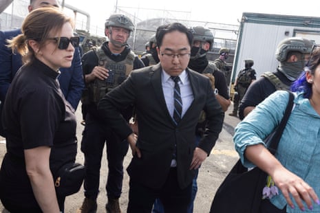 a man in a suit stands among law enforcement agents