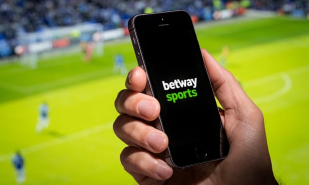 A man looking at the Betway Sports app website whilst watching the football.