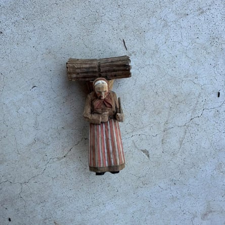 A figurine of an old woman with a bundle of wood on her shoulders.