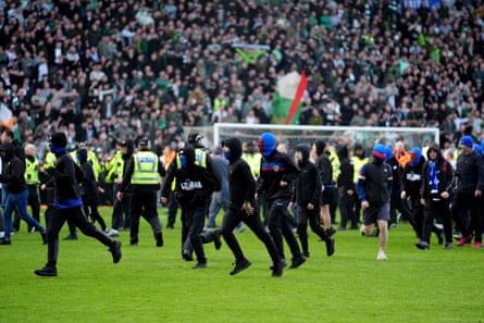 Fans in balaclavas and masks on the pitch at Ibrox