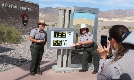 National Park Service rangers are photographed next to a digital display of an unofficial heat reading at Furnace Creek Visitor Center in Death Valley, California, on Sunday.