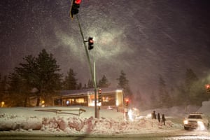 Snow falls as people prepare to cross a street during another winter storm in the Sierra Nevada mountains in California, US