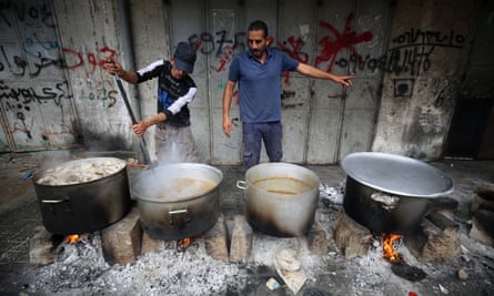 People cook on firewood, amid shortages of fuel and gas, to provide food for displaced Palestinians in southern Gaza.