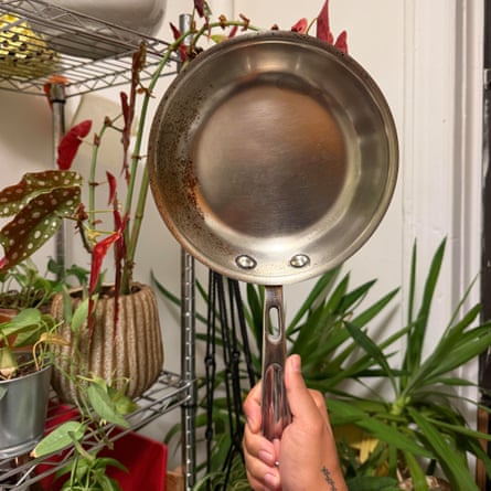 a person holding up a pan from an All-Clad 10-piece Copper-core Cookware Set