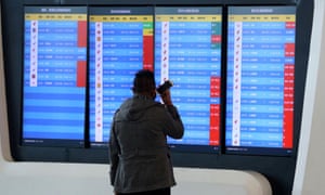 A man stands in front of a screen showing cancelled flights at the airport in Wuhan