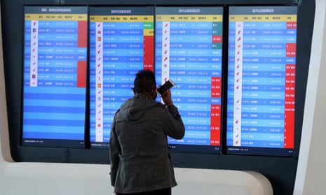 A man stands in front of a screen showing cancelled flights at the airport in Wuhan