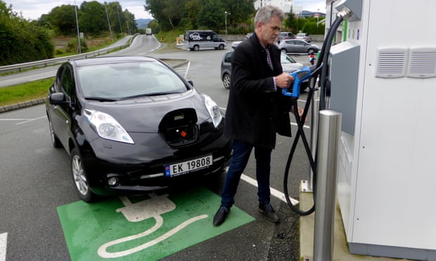 A man recharges his Nissan Leaf electric car in Norway.