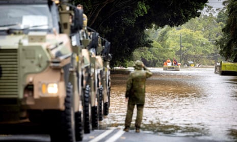 A soldier looks out over a flooded street in Lismore