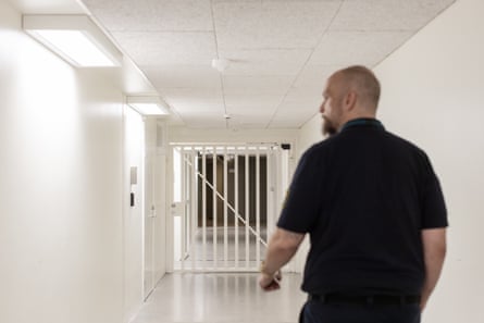 Martin Midner, a prison officer at Kumla, walks through a white corridor heading towards a large white prison gate