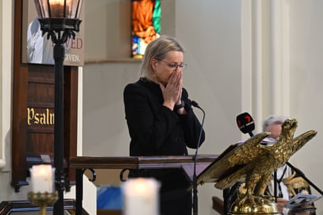 A woman with blond hair and a black outfit stands in a church.