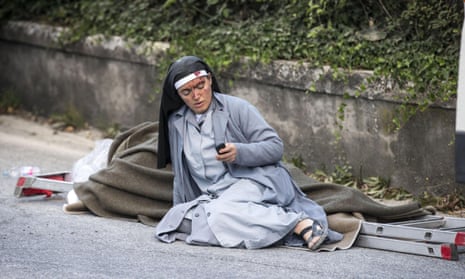 A nun checks her mobile phone as she lies near a victim laid on a ladder following an earthquake in Amatrice Italy, Wednesday, Aug. 24, 2016. The magnitude 6 quake struck at 3:36 a.m. (0136 GMT) and was felt across a broad swath of central Italy, including Rome where residents of the capital felt a long swaying followed by aftershocks. (Massimo Percossi/ANSA via AP)