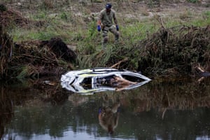 a man stands on land above a submerged car