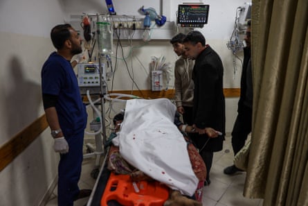 A doctor and two men surround a hospital bed