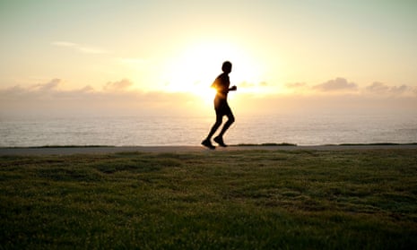 A silhouette of a jogger with sun on horizon