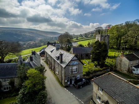 A pub on a hillside in a village with moors in the distance