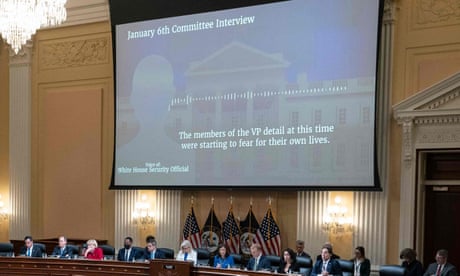 A large screen is displayed in a formal gathering room filled with people.