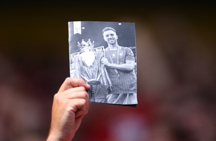 A Liverpool fan holds a photo in memory of Diogo Jota before the match against Preston