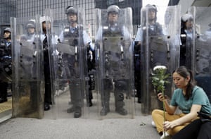 A female protester holds flowers as she sits in front of policemen in anti-riot gear outside the Legislative Council in Hong Kong.