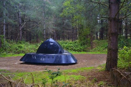 A black, triangular spaceship in a forest clearing