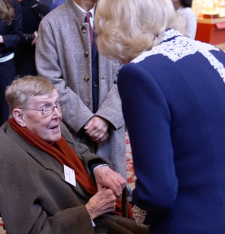 Videograb of Alan Bennett sitting down and looking up at Queen Camilla, who is leaning towards him with her back to the camera, at a reception for authors, illustrators and binders who have been involved in the miniature library collection displayed alongside Queen Mary’s Dolls’ House at Windsor Castle