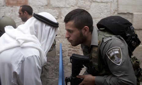 Israeli border policeman speaks to a Palestinian man near the scene of a stabbing in Jerusalem’s Old City