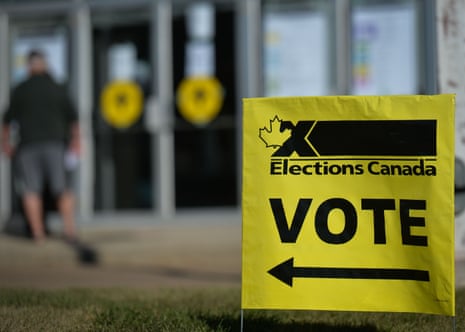 A yellow sign points the way to a polling place with the words "Elections Canada" and "VOTE" on it.