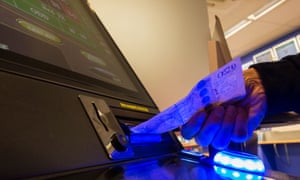 A man feeds a £20 note into a fixed-odds betting terminal.