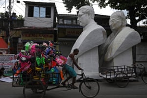 Kolkata, India. A man rides a rickshaw loaded with tricycles past the statues of Mahatma Gandhi and Bangladesh’s founder Sheikh Mujibur Rahman, before their installation near a railway station as part of the golden jubilee celebration of Bangladesh’s independence