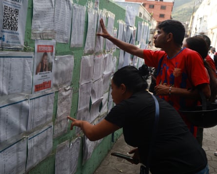 People searching through missing persons lists stuck on a wall
